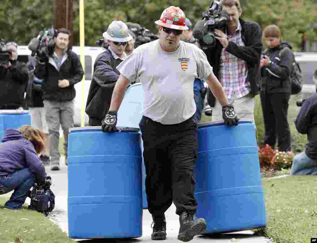 Workers move disposal barrels to a staging area outside the apartment of a health care worker who treated Ebola patient Thomas Eric Duncan and tested positive for the disease, in Dallas, Oct. 13, 2014. 