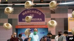Costumers wear masks amid the new coronavirus pandemic, inside the Madureira market where hats hang as decoration, in Rio de Janeiro, Brazil, June 17, 2020. 
