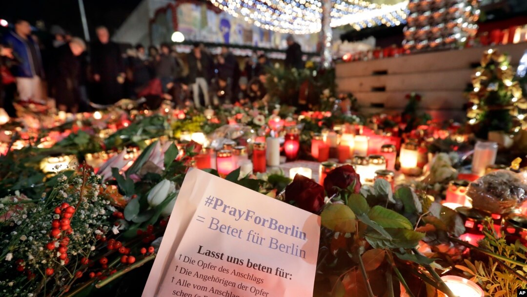 Warga berkumpul di depan lilin-lilin dekat pasar Natal di gereja memorial Kaiser Wilhelm di Berlin, Jerman (21/12), dua hari setelah serangan truk maut. (AP/Michael Sohn)