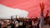 People wear T-shirts that read "Replace the President in 2019" stand under a large national flag during a rally in Jakarta, Indonesia, May 6, 2018. 