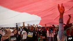 People wear T-shirts that read "Replace the President in 2019" stand under a large national flag during a rally in Jakarta, Indonesia, May 6, 2018. 