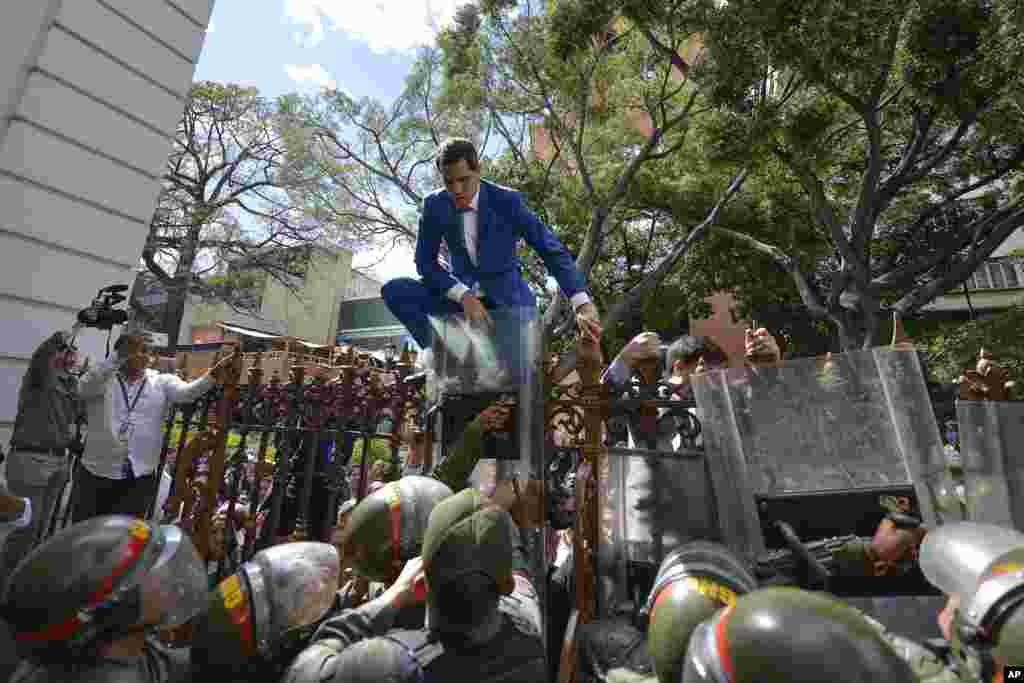 Venezuela&rsquo;s National Assembly President and opposition leader Juan Guaido tries to climb the fence to enter the compound of the Assembly in Caracas, after he and other opposition lawmakers were blocked by police from entering a session to elect new Assembly, Jan. 5, 2020.