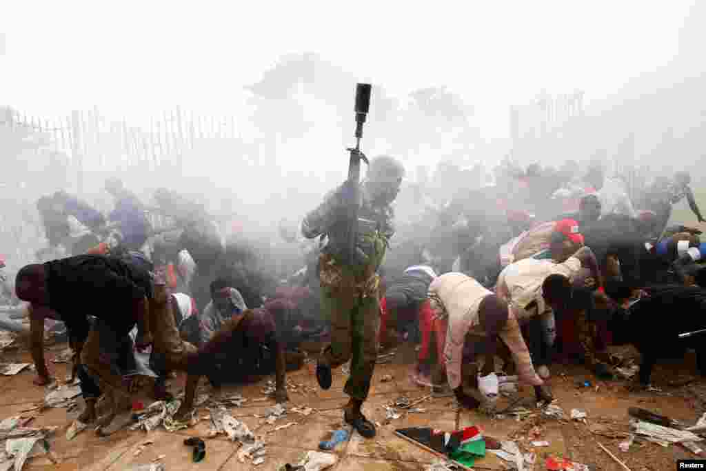 People fall as police fire tear gas to try control a crowd trying to force their way into a stadium to attend the inauguration of President Uhuru Kenyatta at Kasarani Stadium in Nairobi, Kenya.