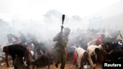 People fall as police fire tear gas to try control a crowd trying to force their way into a stadium to attend the inauguration of President Uhuru Kenyatta. (File)
