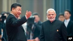 FILE - Chinese President Xi Jinping, left, welcomes Indian Prime Minister Narendra Modi for a meeting at a Shanghai Cooperation Organization summit in Qingdao in eastern China's Shandong province, June 10, 2018. 