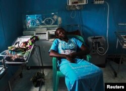 A woman sleeps next to her newborn baby in a nursery in the Juba Teaching Hospital, April 3, 2013. Very few births in South Sudan are assisted by trained midwives.