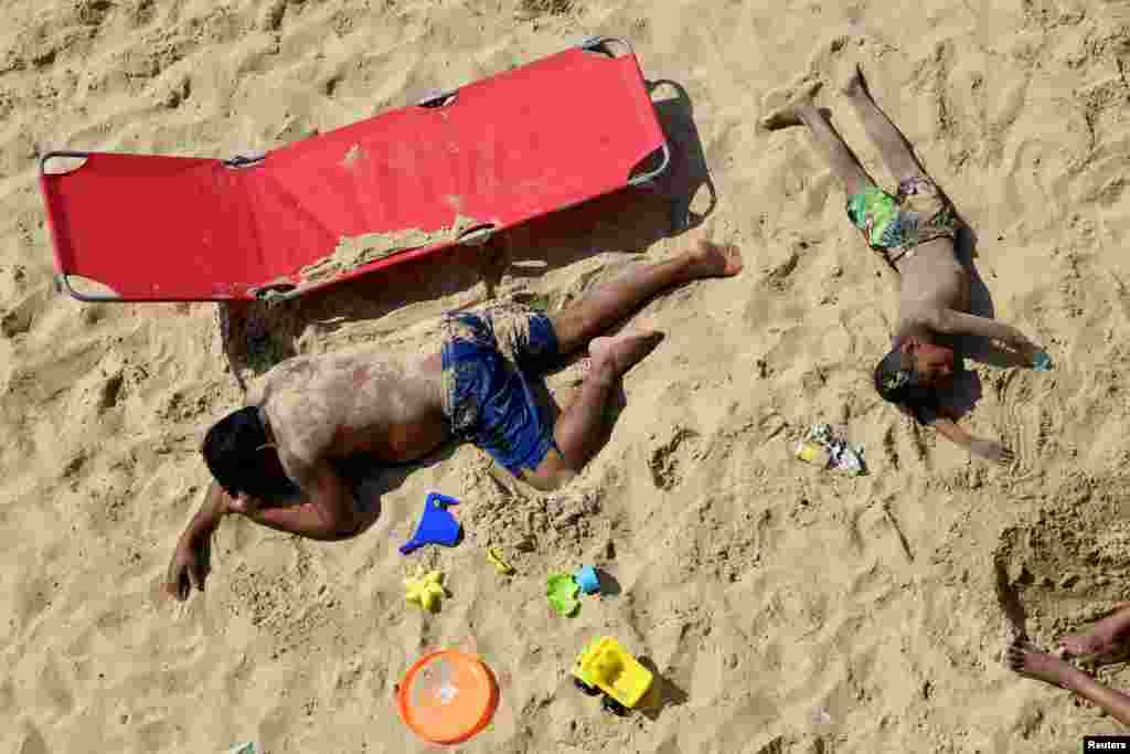 People rest at the Bournemouth Beach, on what is one of Britain&#39;s hottest days of the year so far, amid the coronavirus disease outbreak, in Bournemouth, Britain.