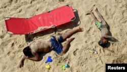 People rest at the Bournemouth Beach, on what is one of Britain's hottest days of the year so far, amid the coronavirus disease outbreak, in Bournemouth, Britain.