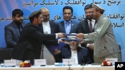 Amin Karim, representative of Gulbuddin Hekmatyar, right, and Attaurahman Saleem, head of delegation at peace talks, left, exchange documents after signing a peace deal in Kabul, Afghanistan, Thursday, Sept. 22, 2016.