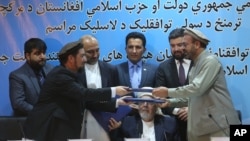 Amin Karim, representative of Gulbuddin Hekmatyar, right, and Attaurahman Saleem, head of delegation of peace talks, left, exchange documents after signing a peace deal in Kabul, Afghanistan, Thursday, Sept. 22, 2016.