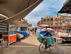 A street vendor rides his bicycle past closed shops in a nearly empty popular market during a curfew to help fight the spread of the coronavirus in the eastern suburb of Baghdad, Iraq, April 3, 2020.