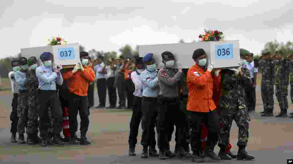 Des membres de l'Agence nationale de recherche et de sauvetage et des soldats indonésiens portent les cercueils des victimes qui étaient à bord de vols AirAsia 8501 à l'aéroport de Pangkalan Bun, l'Indonésie, le 5 janvier 2015.