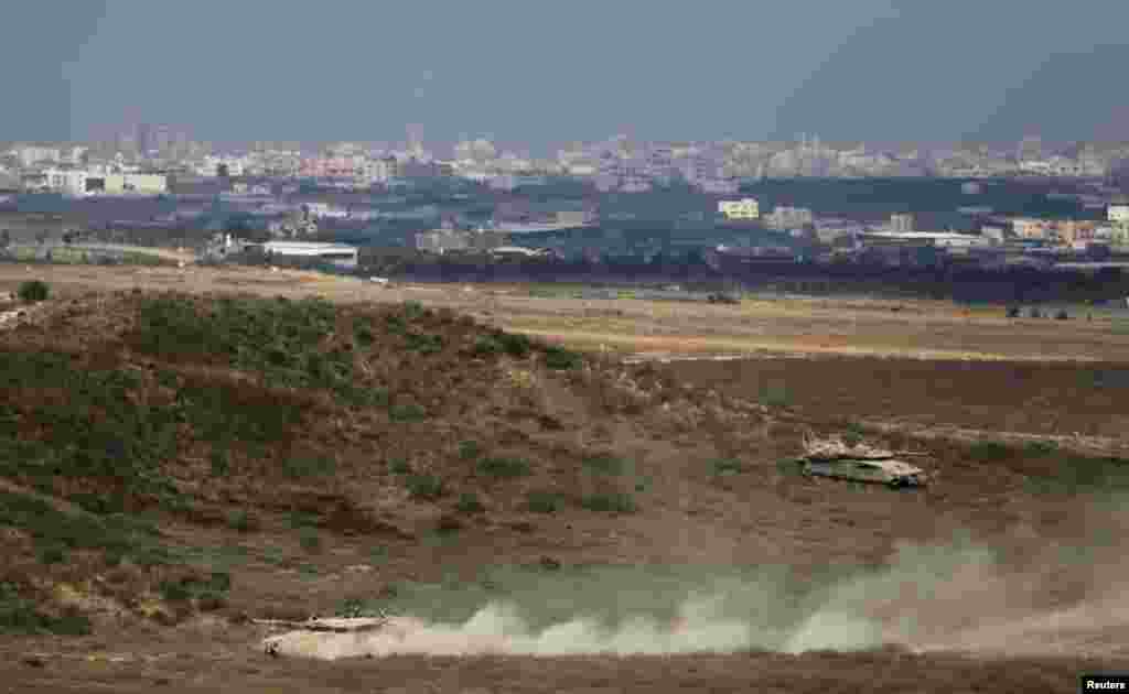 Israeli tanks can be seen as they drive on the Israeli side of the border with Gaza, August 8, 2014.