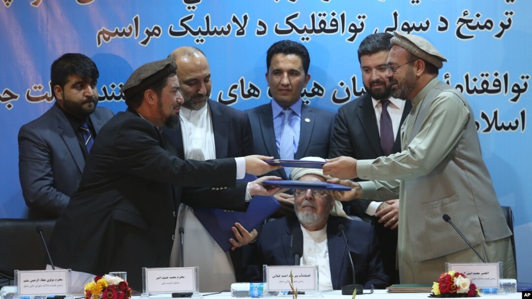 Perwakilan pemerintah Afghanistan, Attaurahman Saleem (kiri) dan Amin Karim, wakil dari kelompok Hizb-Islami (HIG), bertukar dokumen usai penandatanganan perjanjian damai di Kabul, Afghanistan, Kamis (22/9).