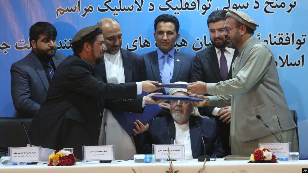 FILE -- Amin Karim, representative of Gulbuddin Hekmatyar, right, and Attaurahman Saleem, head of delegation of peace talks, left, exchange documents after signing a peace deal in Kabul, Afghanistan, Thursday, Sept. 22, 2016.