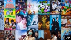 Los visitantes pasan frente a una exhibición de carteles de producciones cinematográficas y televisivas chinas en la Feria Internacional de Comercio de Servicios de China en Beijing, el 3 de septiembre de 2021.