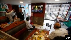 Clientes en un restaurante de Lima, Perú, observan en un televisor el debate en el Congreso que busca la destitución del presidente Pedro Pablo Kuczynski. Dic.21 de 2017.