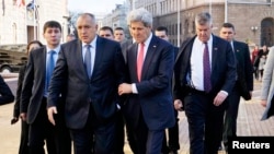 U.S. Secretary of State John Kerry holds onto Bulgarian Prime Minister Boyko Borisov as they walk around a patch of ice on the sidewalk after holding a joint news conference in Sofia, Jan. 15, 2015. 