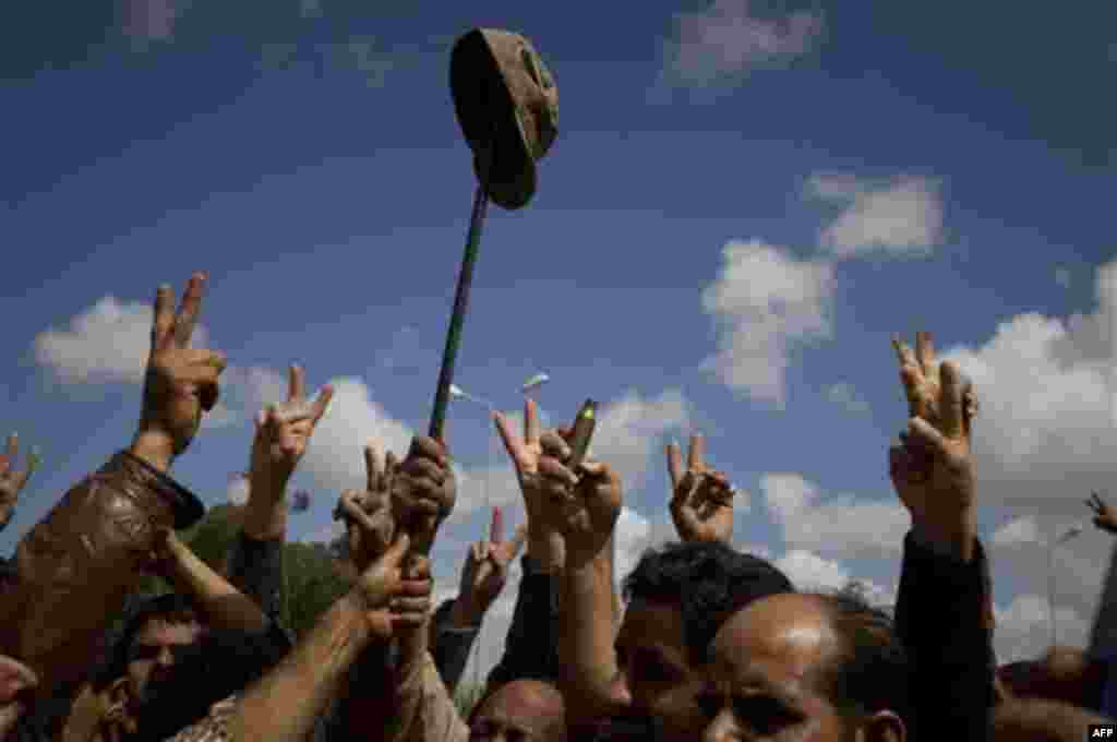 Libyan rebels celebrate with an army cap from a soldier loyal to Moammar Gadhafi in the outskirts of Benghazi, eastern Libya, Sunday, March 20, 2011. The U.S. military said 112 Tomahawk cruise missiles were fired from American and British ships and submar