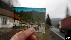 In this photo taken on Thursday, Jan. 23, 2020, an old postcard shows how the village of Blagojev Kamen, Serbia looked like fifty years ago. (AP Photo/Darko Vojinovic)