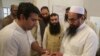 An election officer marks a thumb of Hafiz Saeed, right, head of the Pakistani religious party Jamaat-ud-Dawa, at polling station in Lahore, Pakistan, July 25, 2018. 