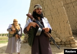 FILE - Taliban walk as they celebrate cease-fire in Ghanikhel district of Nangarhar province, Afghanistan, June 16, 2018.