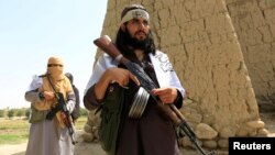 FILE - Members of the Taliban walk in Ghanikhel district of Nangarhar province, Afghanistan, June 16, 2018.