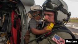 Naval Aircrewman 2nd Class Brandon Larnard, assigned to Helicopter Sea Combat Squadron, carries an evacuee off an MH-60S Sea Hawk helicopter following the landfall of Hurricane Maria on the island of Dominica, Sept. 27, 2017. 