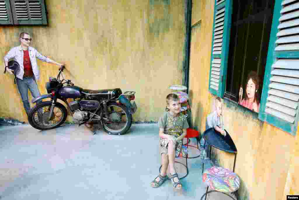 A boy sits near the Soviet-era Minsk motorcycle at a repurposed cafe named Hidden Gem Cafe which contains recyclable objects in Hanoi, Vietnam.