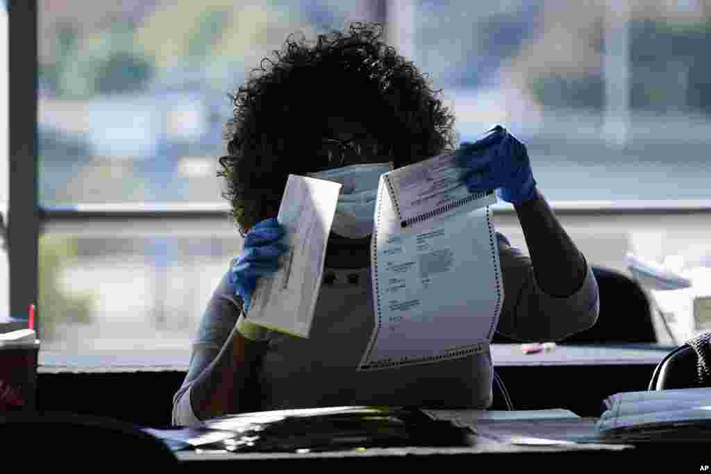 An election worker examines a ballot as vote counting in the general election continues at State Farm Arena in Atlanta, Georgia.