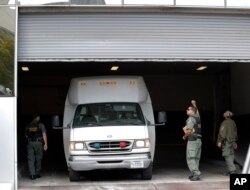 A van carrying asylum seekers from the border is escorted by security personnel as it arrives to immigration court, March 19, 2019, in San Diego, California.