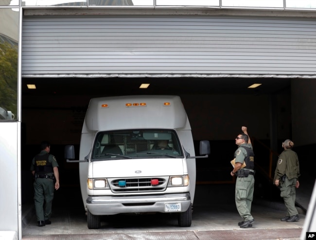 A van carrying asylum seekers from the border is escorted by security personnel as it arrives to immigration court, March 19, 2019, in San Diego, California.