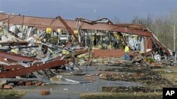 An employee of Henryville High School in Henryville, Indiana, examines the remains of the building following severe storms and tornadoes, March 2, 2012.