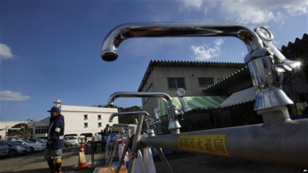 A worker from a water supply department walks by water faucets set up for survivors at a shelter in the devastated town of Yamamoto, Miyagi Prefecture, northeastern Japan, March 28, 2011
