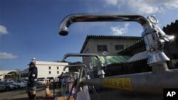 A worker from a water supply department walks by water faucets set up for survivors at a shelter in the devastated town of Yamamoto, Miyagi Prefecture, northeastern Japan, March 28, 2011