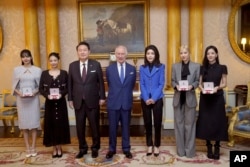 Presiden Korea Selatan Yoon Suk Yeol, Raja Charles III, ibu negara Korea Selatan Kim Keon Hee, Rose (Roseanne Park), dan Jisoo Kim berpose dengan anggota band K-Pop Blackpink. (Foto: via AP)