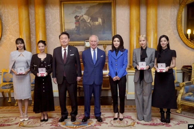 Presiden Korea Selatan Yoon Suk Yeol, Raja Charles III, ibu negara Korea Selatan Kim Keon Hee, Rose (Roseanne Park), dan Jisoo Kim berpose dengan anggota band K-Pop Blackpink. (Foto: via AP)