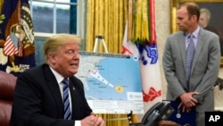 President Donald Trump, left, talks about Hurricane Florence during a briefing in the Oval Office of the White House in Washington, Sept. 11, 2018, as FEMA Administrator Brock Long listens at right. 