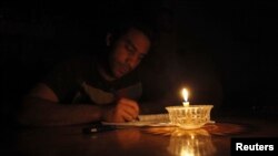 Mostafa Khaled, 20, studies by candlelight for his early morning exams during a power cut in Toukh, about 25 km northeast of Cairo, May 26, 2013.