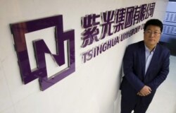 资料照：紫光集团董事长赵伟国站在该集团北京办公室的标识前。（2015年11月15日）