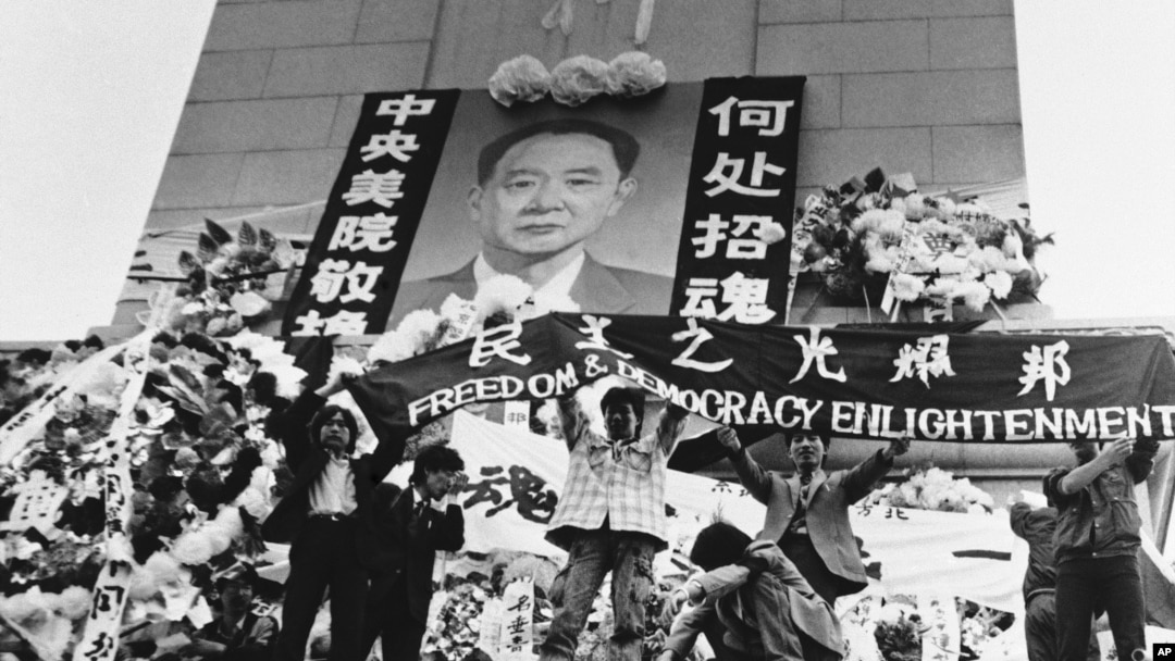 资料照片: 1989年4月19日中国学生在北京天安门广场上的人民英雄纪念碑前展示胡耀邦像和“民主之光耀邦”等标语