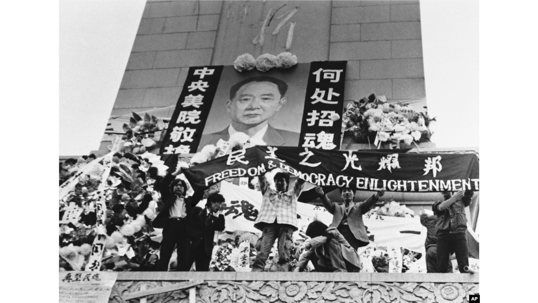 中国学生在北京天安门广场上的人民英雄纪念碑前展示胡耀邦像和“民主之光耀邦”等标语（1989年4月19日）