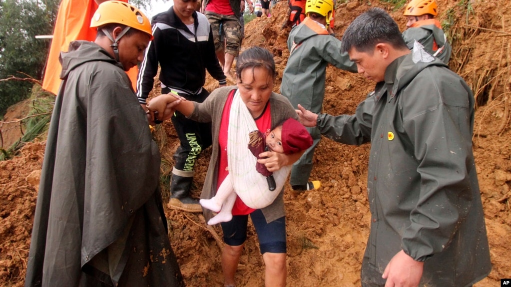 Rescatistas ayudan a una mujer y su hijo para evacuarla a un Ã¡rea mÃ¡s segura luego de derrumbes en el municipio de ItogÃ³n, provincia de Benguet, en el norte de Las Filipinas. Los deslizamientos de tierra, que sepultaron a decenas de mineros y han aislado la poblaciÃ³n son consecuencia del tifÃ³n Mangkhut. Septiembre 16 de 2014.