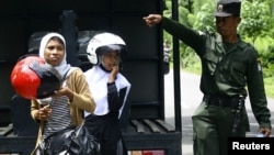 Seorang polisi syariah bersama dua orang perempuan yang ditangkap karena memakai celana ketat dalam razia di distrik Arongan Lambalek di Aceh Barat. (Foto: Dok)