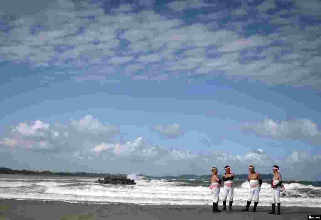 Peserta berdiri di pantai menunggu dimulainya festival &quot;Ohara Hadaka&quot;, yang diadakan sebagai bagian dari perayaan musim gugur dan doa untuk panen yang baik, di Isumi, Prefektur Chiba, Jepang. (Reuters)&nbsp;