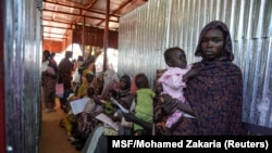 Seorang perempuan tampak menggendong anaknya saat berada di kamp pengungsi Zamzam di Sudan, yang terletak di dekat wilayah El Fasher, di Darfur Utara, pada Januari 2024. (Foto: MSF/Mohamed Zakaria/Handout via Reuters)