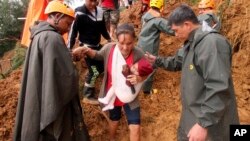 Seorang ibu dan anak dibantu oleh tim penyelamat setelah selamat dari badai Mangkhut yang menghantam kota Itogon, Filipina, Minggu, 16 September 2018. 