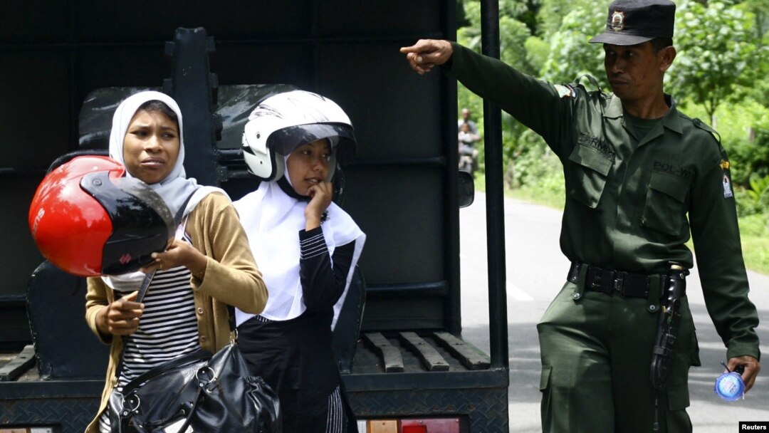 Seorang polisi syariah bersama dua orang perempuan yang ditangkap karena memakai celana ketat dalam razia di distrik Arongan Lambalek di Aceh Barat. (Foto: Dok)