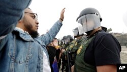 A man faces Border Patrol agents during a protest, Dec. 10, 2018, in San Diego. The protest organized by a Quaker group called for an end to detaining and deporting immigrants and showed support for a caravan of Central American asylum seekers. 