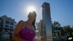 FILE - A woman showers at Sydney's Bondi beach as temperatures in excess of 40 degrees Celsius (104 Fahrenheit) hit parts of eastern Australia on Dec. 9, 2023.